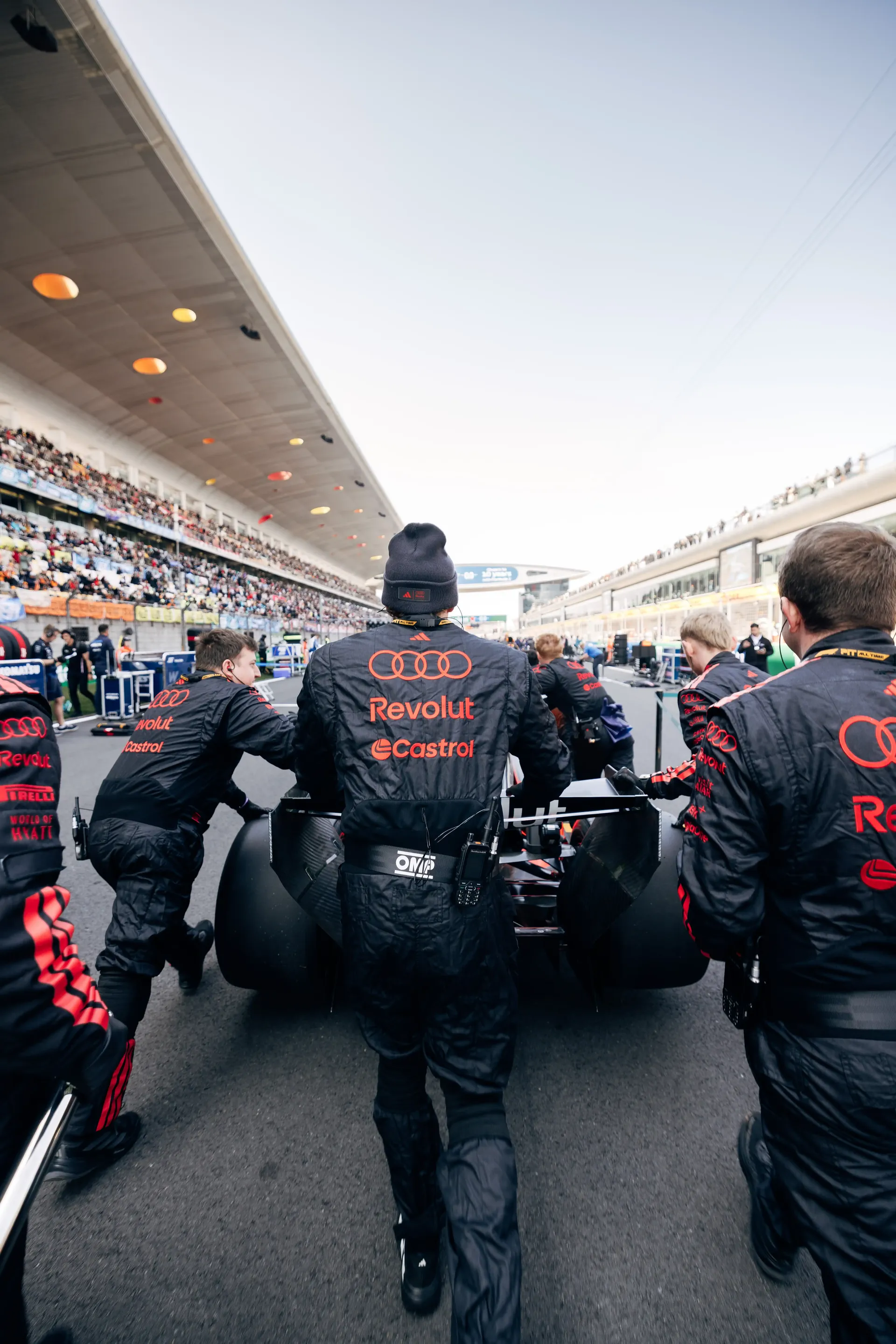 Audi Revolut F1® Team mechanics working on the Formula 1 car in the pit lane garage area.