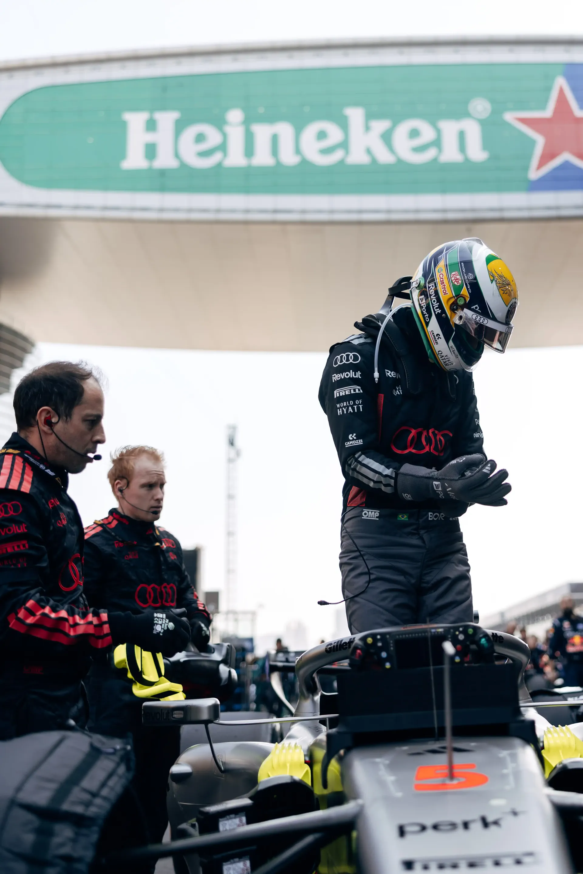 Audi Revolut F1® Team driver walking through the paddock near sponsor signage during the Chinese Grand Prix.