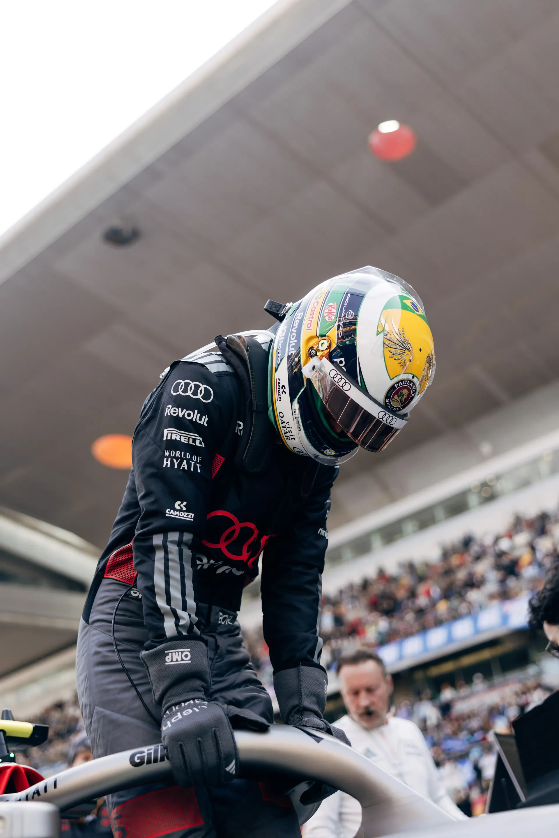 Audi Revolut F1® Team driver Gabriel Bortoleto leaning over the Formula 1 car during pre-race preparation.