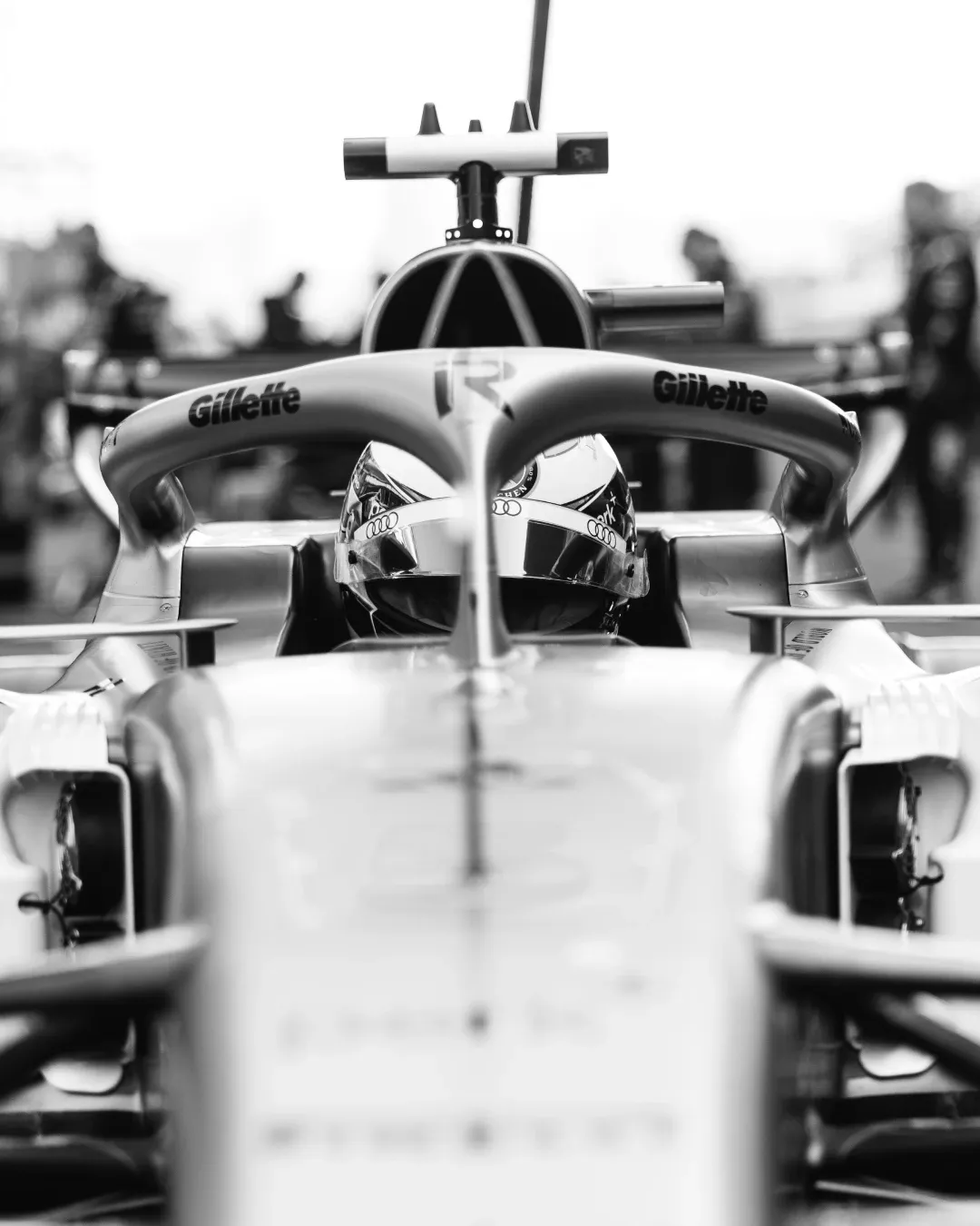 Front view of Nico Hulkenberg seated in the Audi Revolut F1® Team car in black and white, with his helmet visible behind the halo in the Shanghai garage.