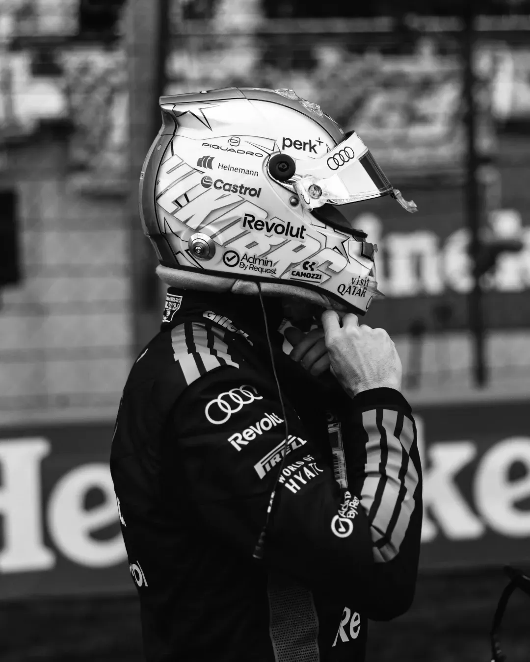 Nico Hulkenberg stands trackside in full Audi Revolut F1® Team race kit, adjusting his helmet strap before a session in Shanghai.