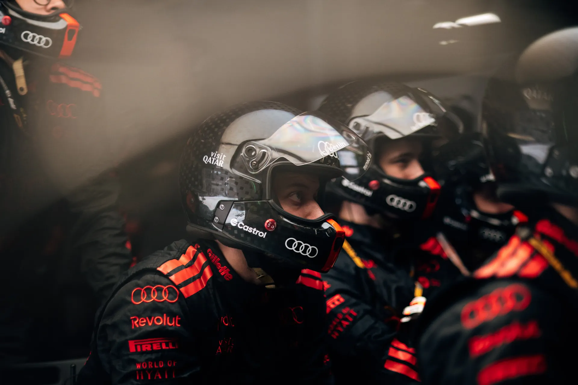 Audi Revolut F1® Team pit crew wearing helmets and preparing for action inside the Formula 1 garage.