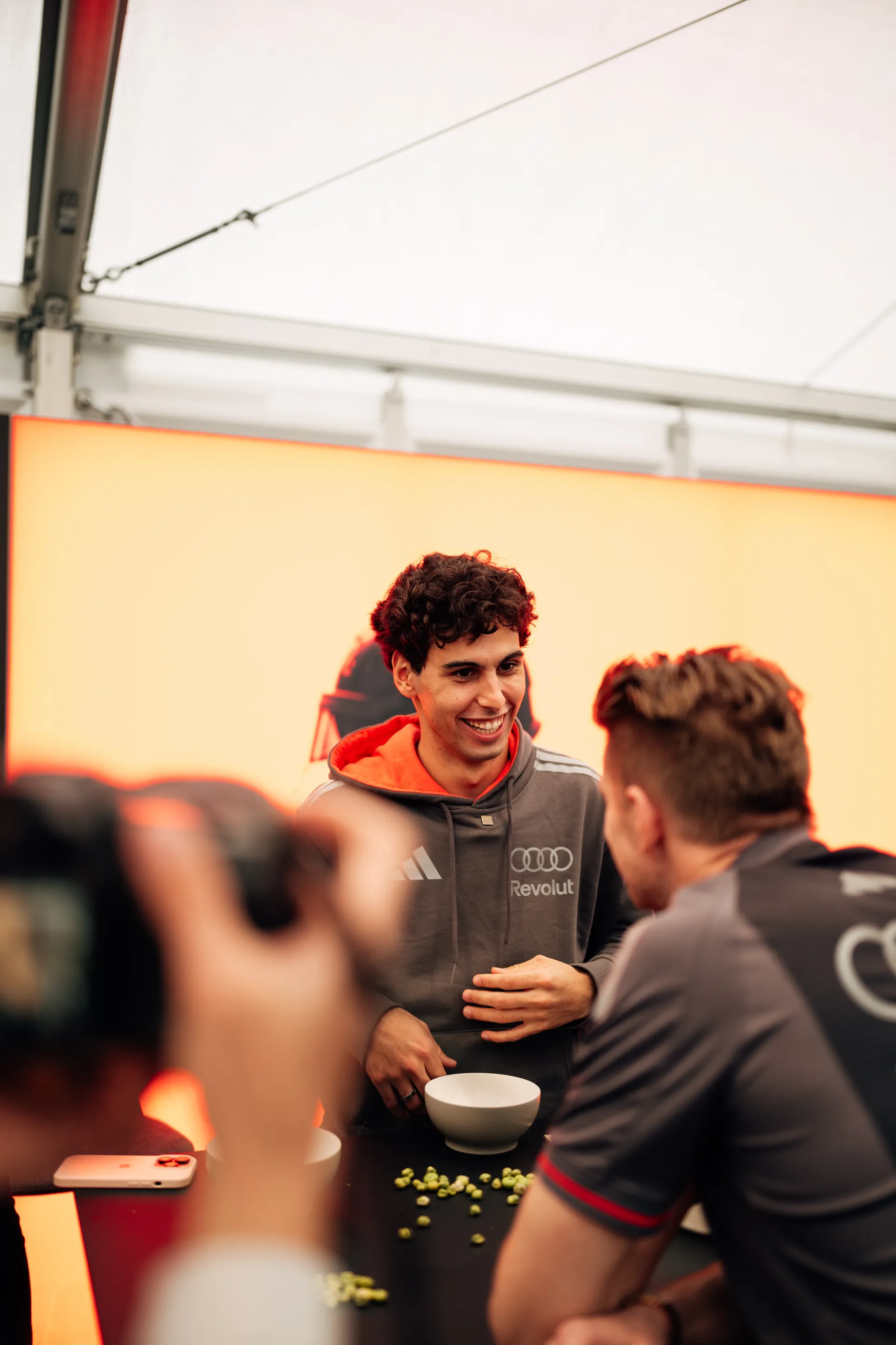 Gabriel Bortoleto smiles during an activation at the Audi Revolut F1® Team hospitality area with Nico Hulkenberg in the foreground.