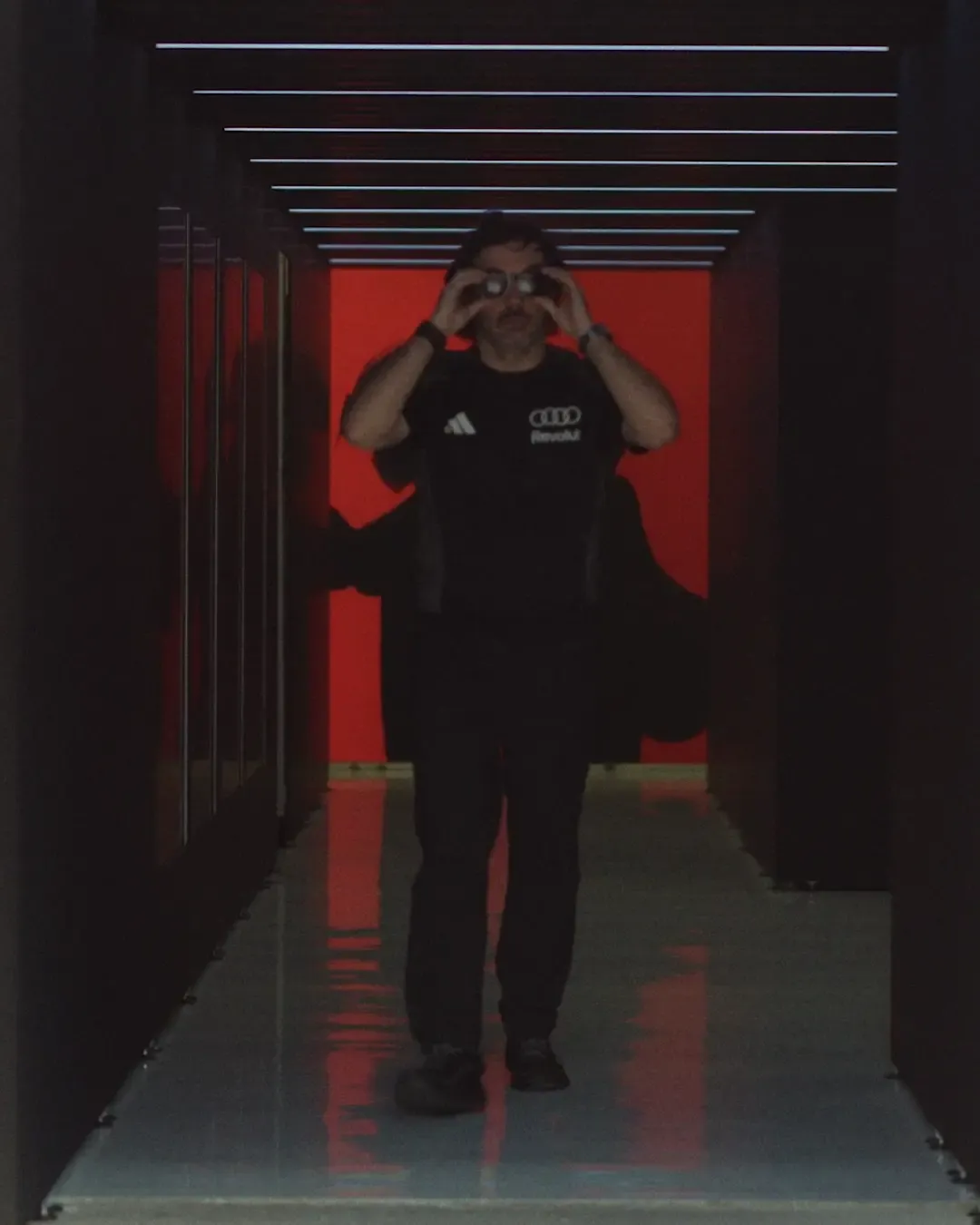 Formula 1 Racing crew member walks towards the camera, all in Audi Revolut F1® Team kit, walking busy outside and getting ready for Raceday