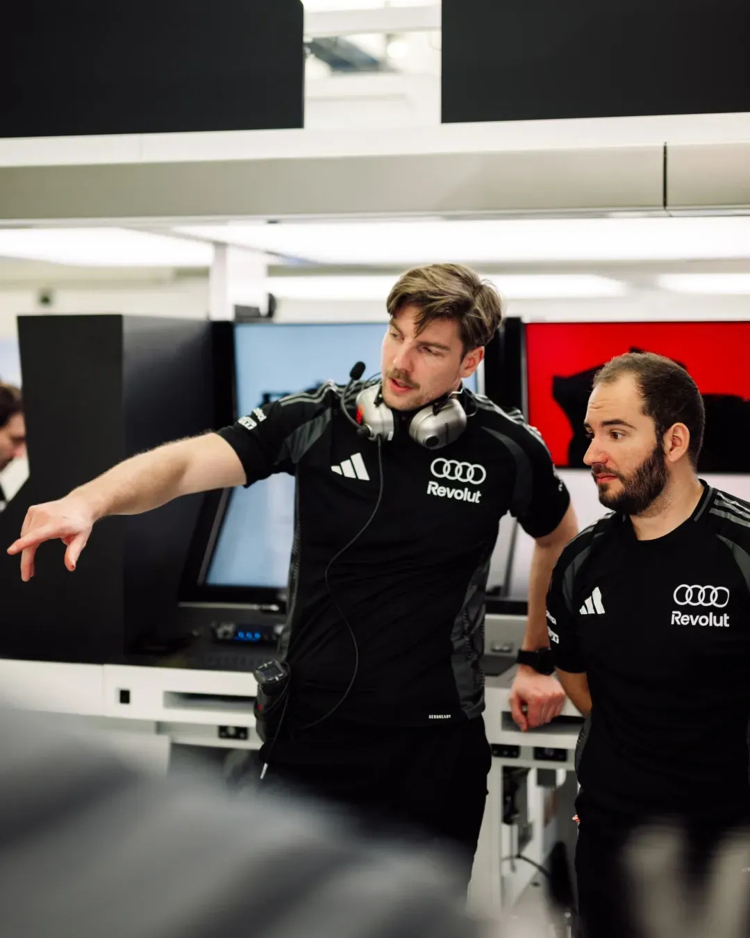 Two Audi Revolut F1® Team engineers review data and point at a monitor during Bahrain test week