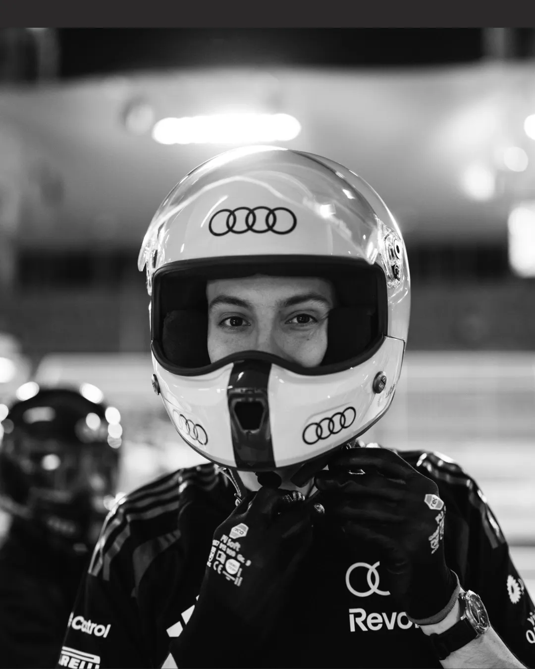 Black and white portrait of a team member wearing an Audi-branded helmet.