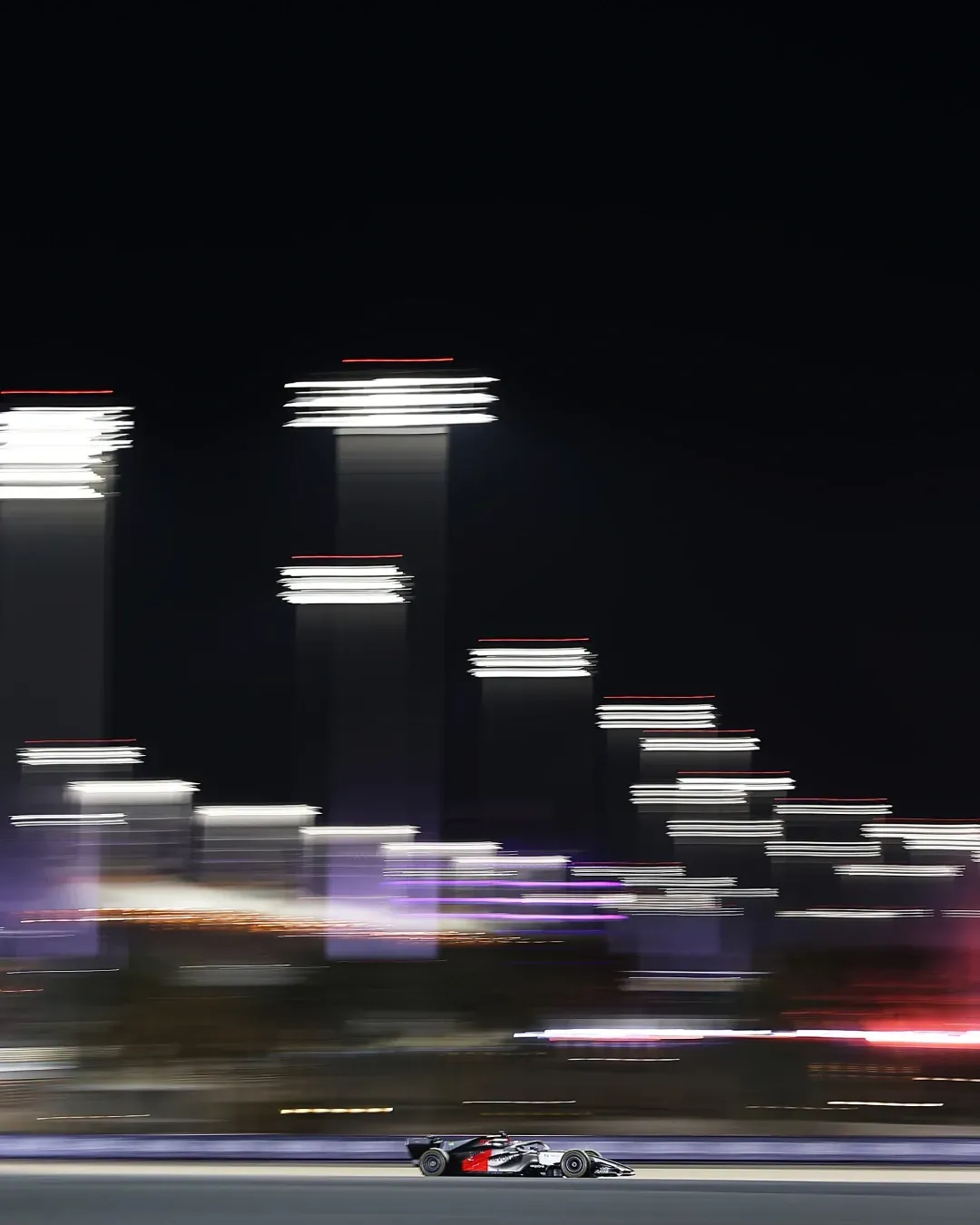 Night track scene with long exposure lights and the car racing along the bottom.