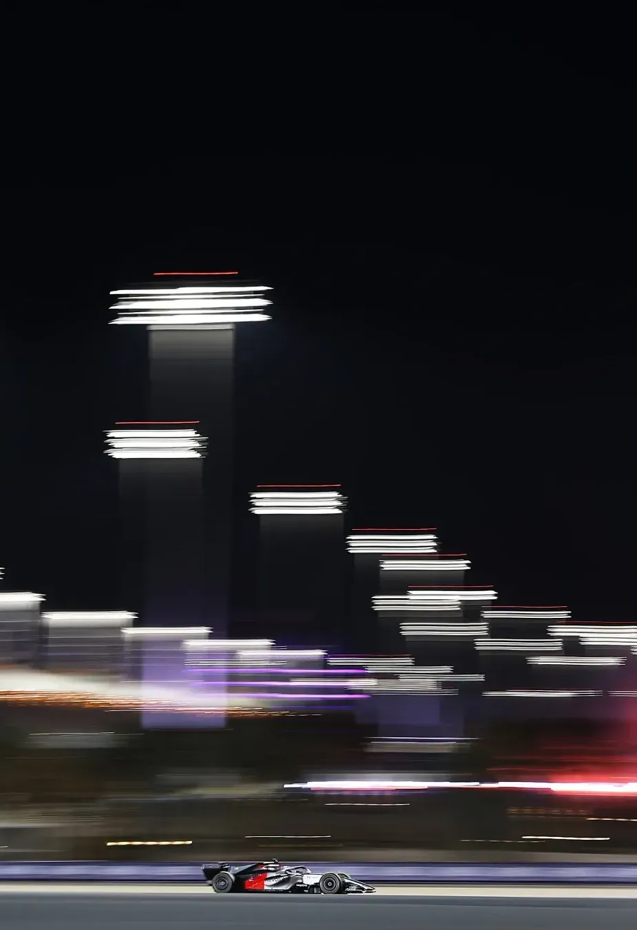 Night track scene with long exposure lights and the car racing along the bottom.