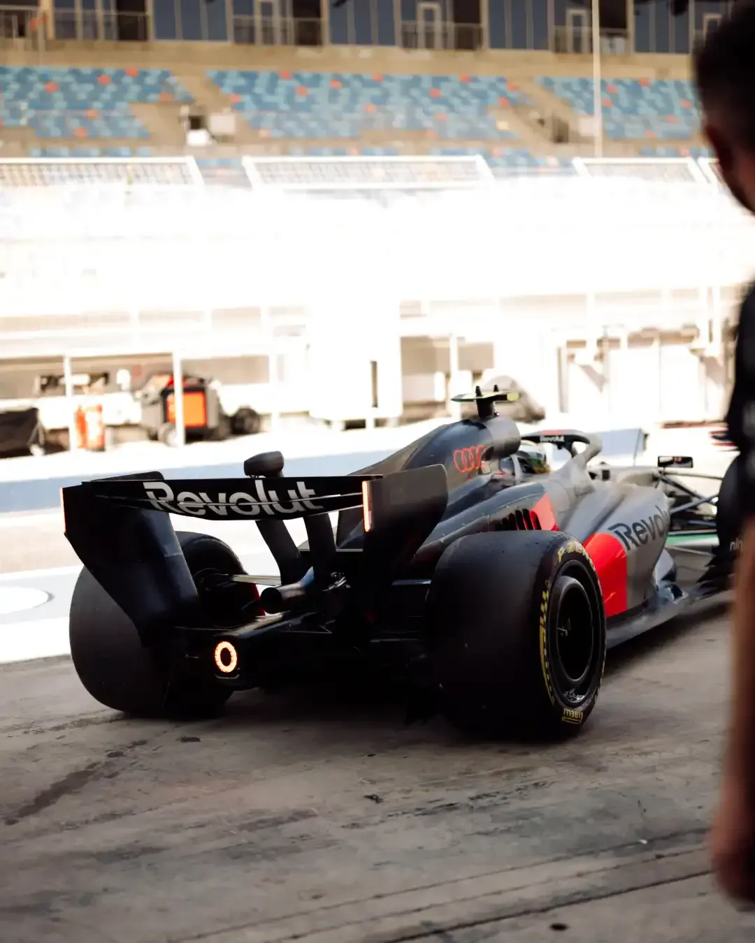Rear view of the Audi Revolut F1® car leaving the garage into the pit lane, rear light glowing.