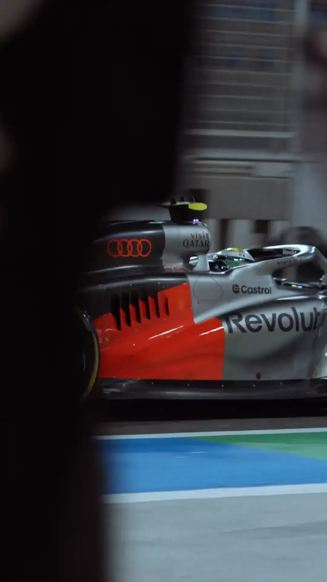 Front three quarter-view of the Audi Revolut F1® car in the garage, crew blurred in the background.