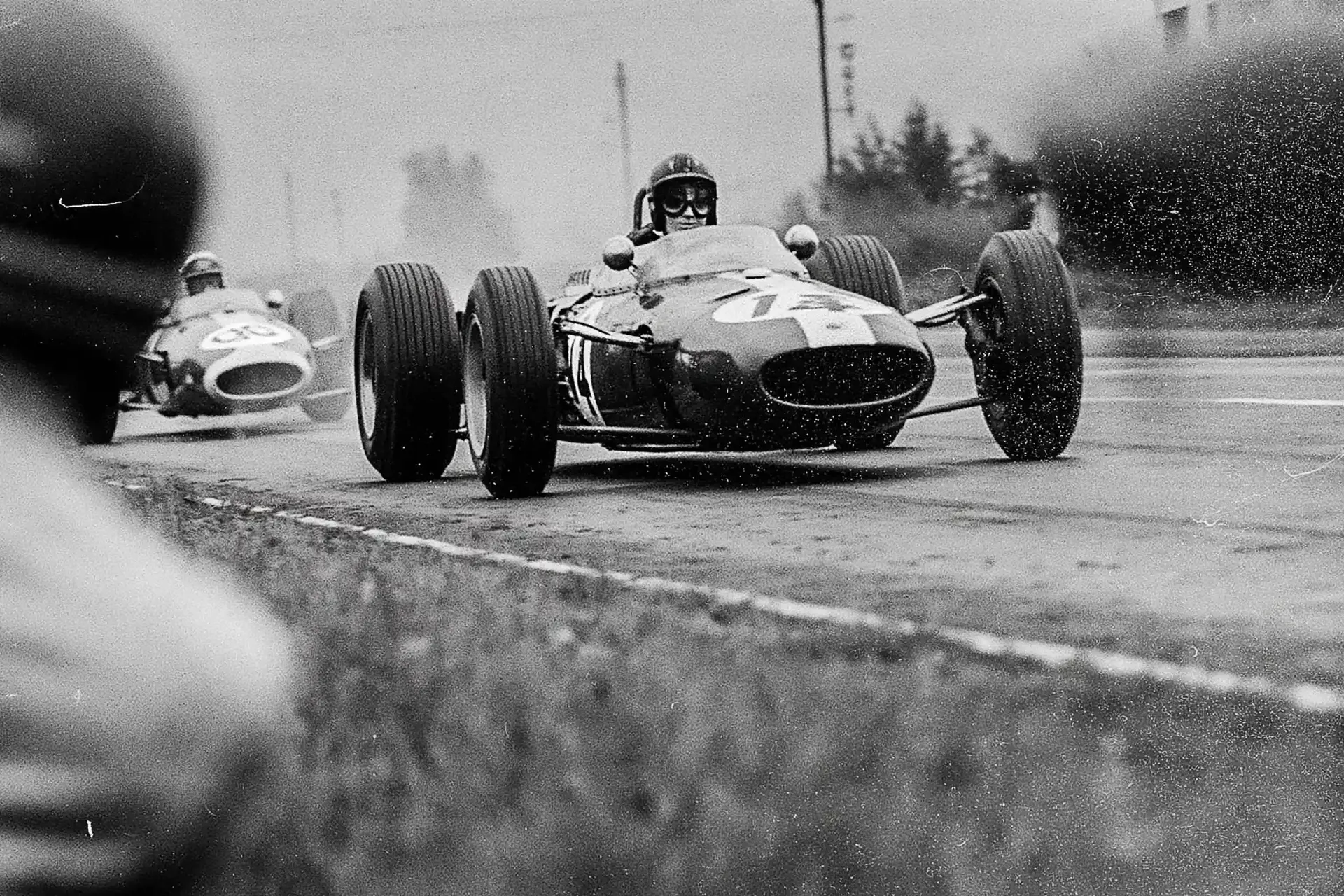 Historic Grand Prix race action at Zeltweg Air Base in rainy conditions.