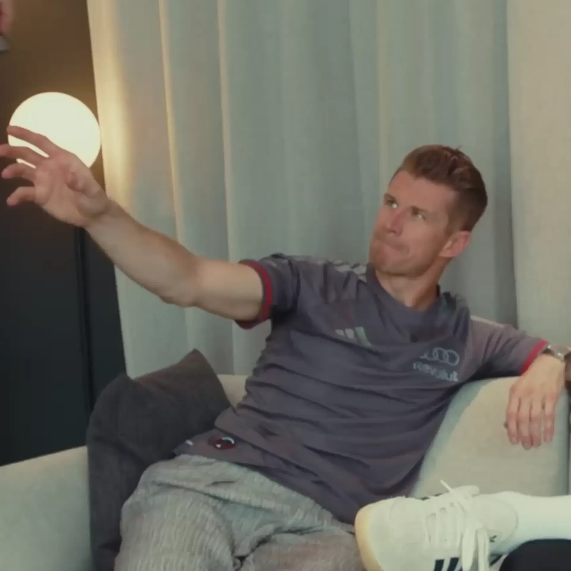 Nico Hulkenberg takes the camera leaning back while seated, in a cozy appartment