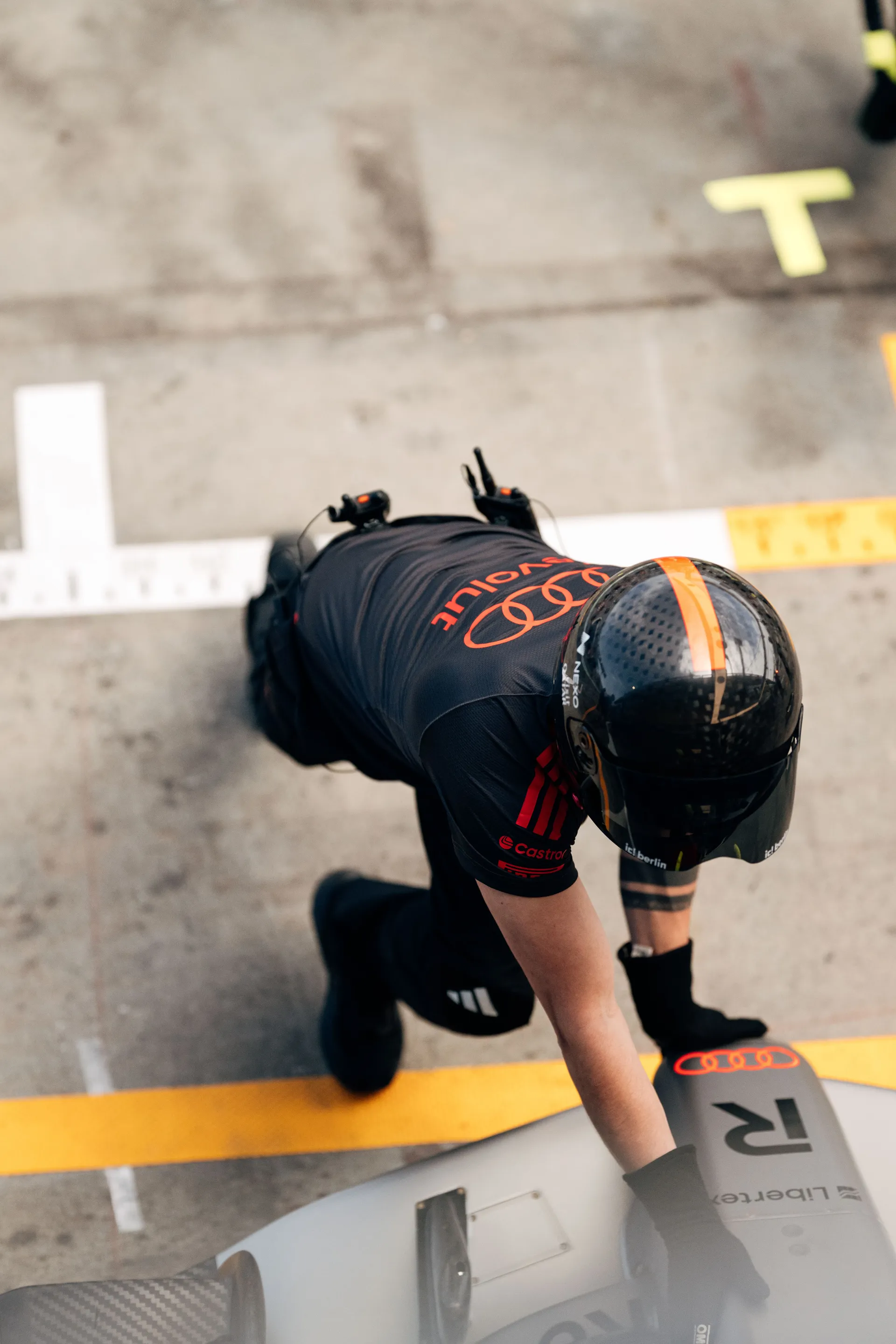 Overhead view of an Audi Revolut F1® Team crew member working on the front of the car in the pit lane.