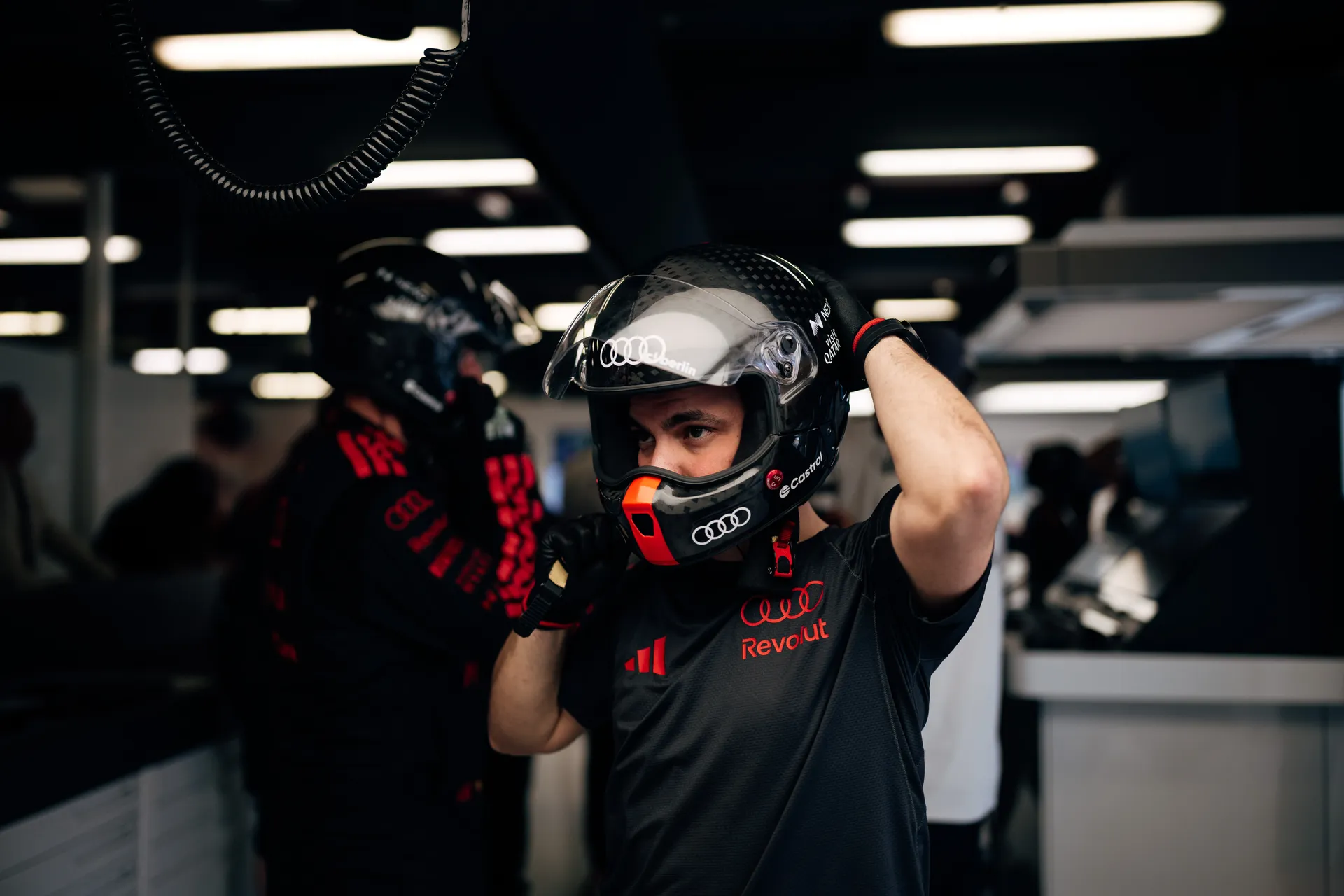 An Audi Revolut F1® Team crew member adjusts a helmet inside the garage before going out to work.