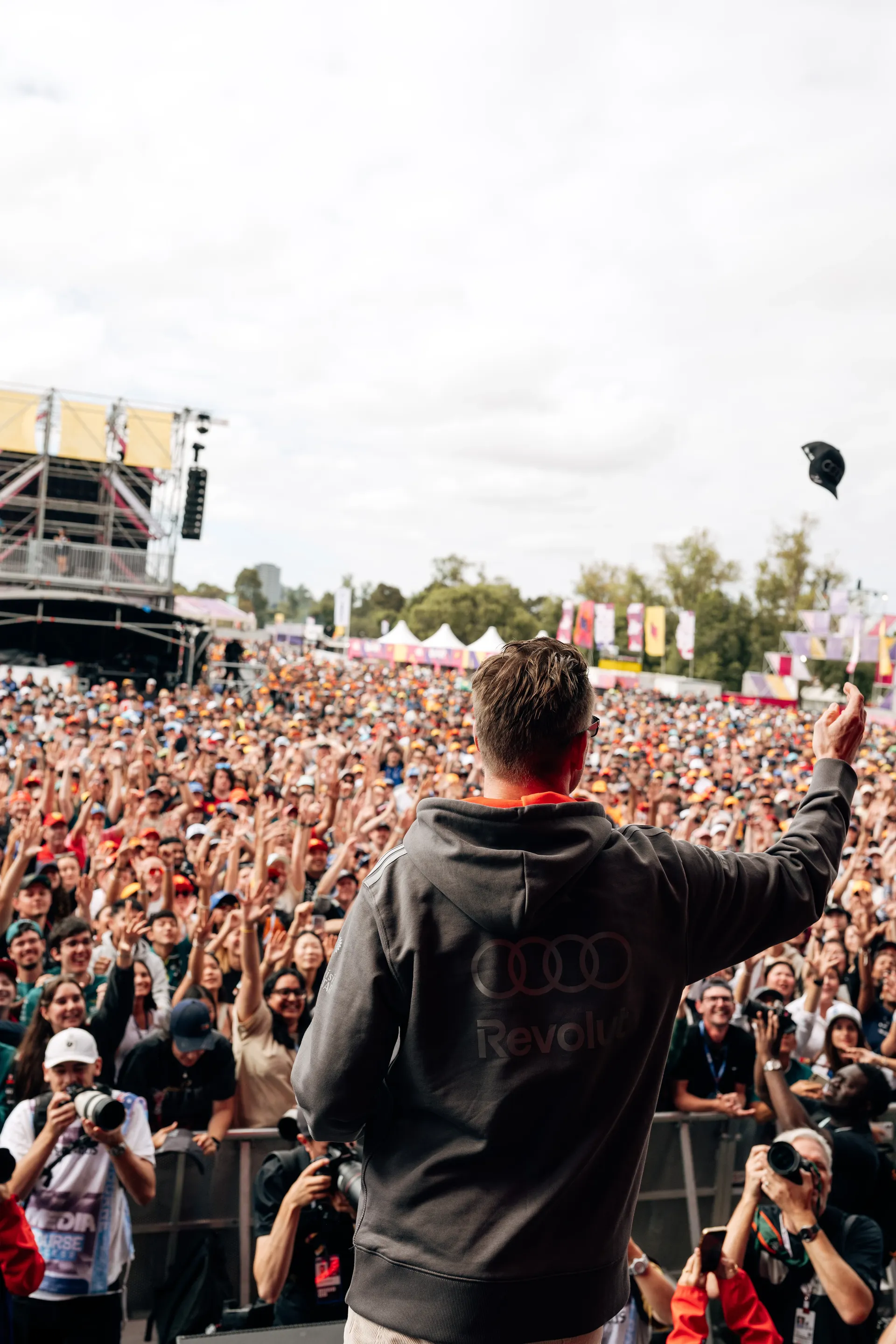 An Audi Revolut F1® Team driver Gabriel Bortoleto throws a cap into the crowd during a live fan appearance in Melbourne.