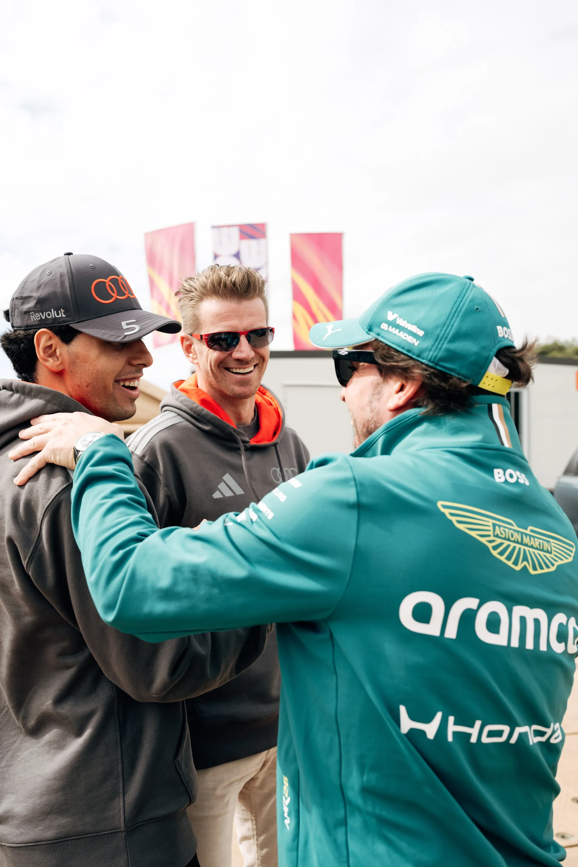 An Audi Revolut F1® Team driver Niko Hulkenberg and Gabriel Bortoleto greets a rival Formula 1 driver in the paddock area during Melbourne race week.