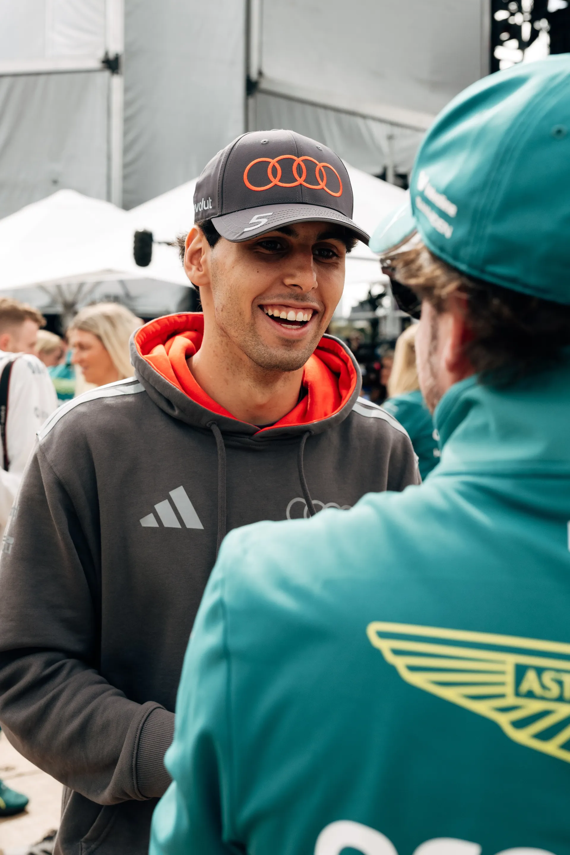 Close up of an Audi Revolut F1® Team driver Gabriel Bortoleto  smiling during a paddock conversation with a rival Formula 1 driver in Melbourne.