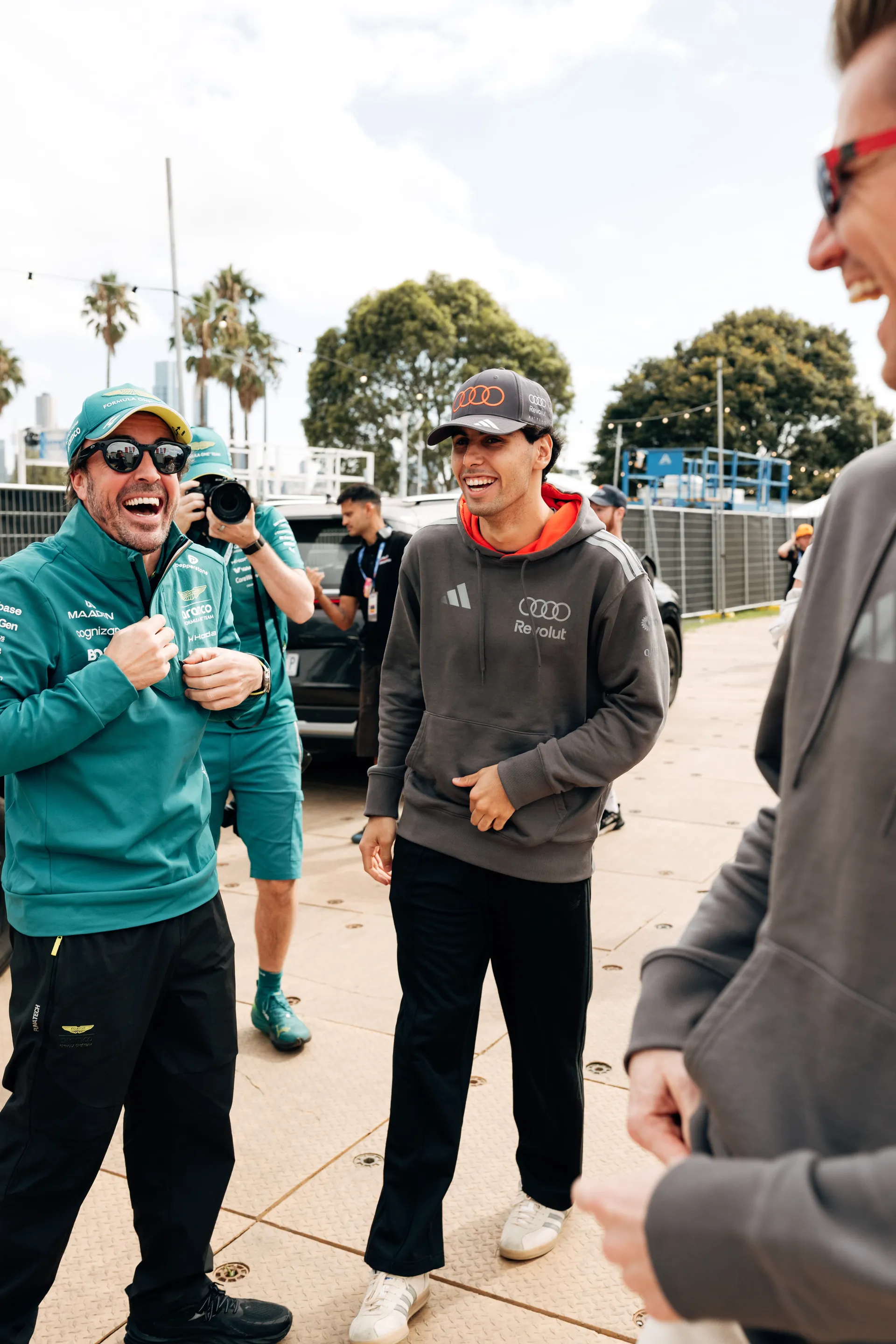 An Audi Revolut F1® Team driver Niko Hulkenberg and Gabriel Bortoleto  laughs with a rival Formula 1 driver in the paddock during Melbourne Grand Prix week.
